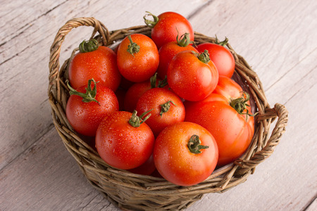 tomatoes in a cute basket on a wooden tableの写真素材