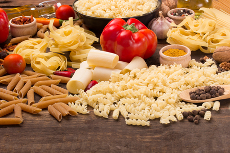 various pasta with food ingredients on dark wooden tableの写真素材