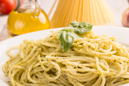 closeup of spaghetti with pesto sauce with ingrediends in the backgroundの写真素材