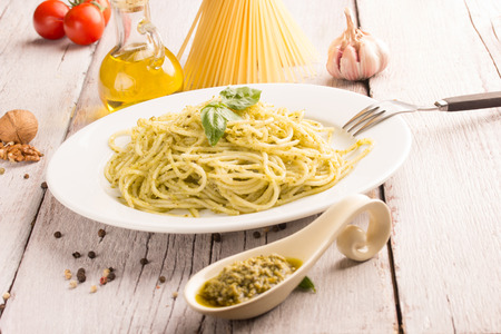 spaghetti with green pesto sauce on white wooden tableの写真素材