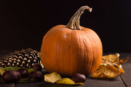 pumpkin with chestnut and autumn leaves on a wooden surfaceの写真素材