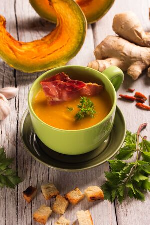pumpkin soup with ingredients on a white wooden tableの写真素材