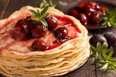 Stack of freshly baked pancakes with plumes and mintの写真素材