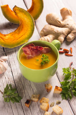 pumpkin soup with ingredients on a white wooden tableの写真素材
