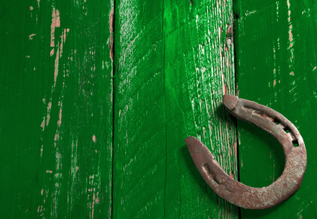 Old rusty horseshoe on vintage green wooden boardの写真素材