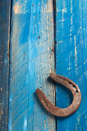 Old  iron metal horse shoeing accessory horseshoe on wood backgroundの写真素材