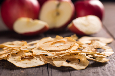 closeup of dried apple slices with red apples in the backgroundの写真素材