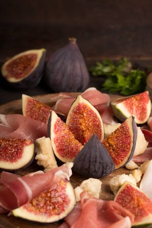 Figs with ham and cheese on a rustic wooden table, food still lifeの写真素材