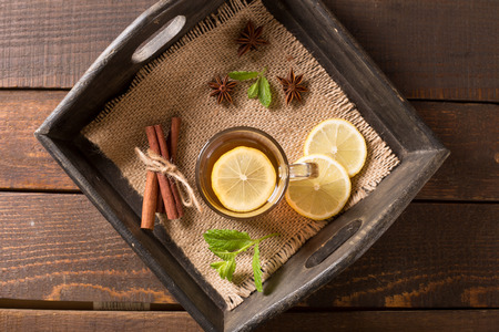 Transparent cup of green tea with cinnamon on wooden backgroundの写真素材