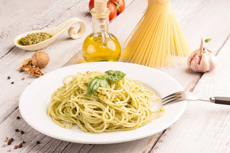 spaghetti with pesto sauce on white wooden tableの写真素材
