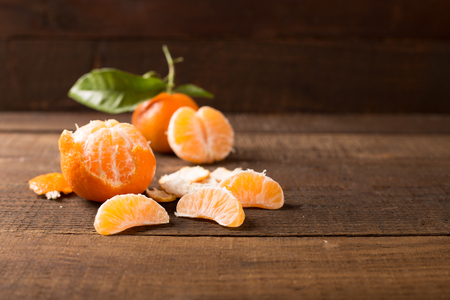 Ripe juicy tangerine, orange mandarin with leaves on wooden tableの写真素材