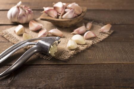 Garlic and garlic press on rustic wooden boardの写真素材