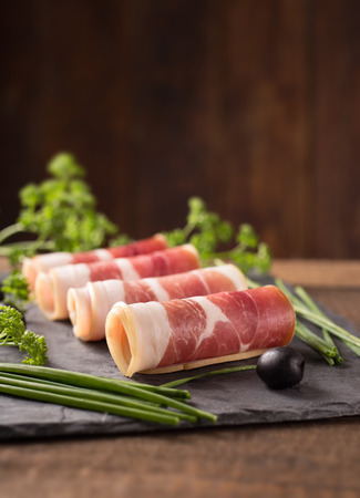 Delicious sliced bacon on wooden table with herbsの写真素材