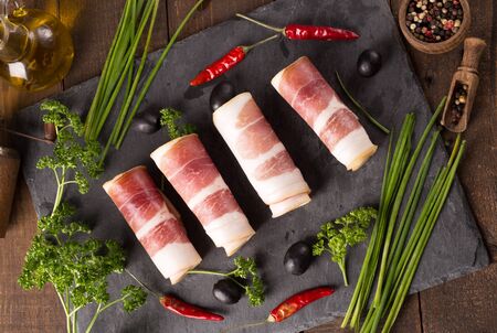 Delicious sliced bacon on wooden table with herbsの写真素材