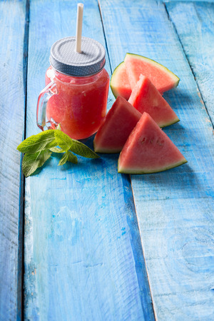 Watermelon smothie and slices with on blue wooden backgroundの写真素材