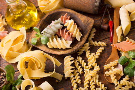 Various mix of pasta on wooden rustic background; Diet and food concept. Colored natural pasta. Spinach, beetroot, eggの写真素材