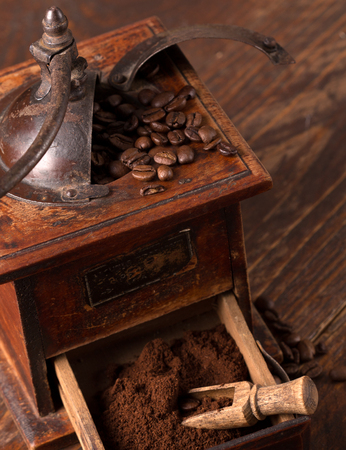 vintage coffee grinder with beans scattered around it の写真素材