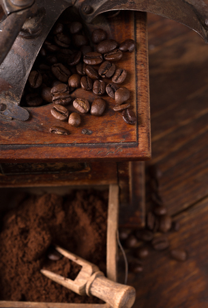 vintage coffee grinder with beans scattered around it の写真素材