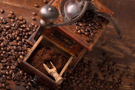vintage coffee grinder with beans scattered around it の写真素材