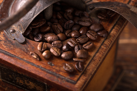 vintage coffee grinder with beans scattered around it の写真素材
