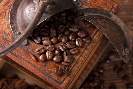 vintage coffee grinder with beans scattered around it の写真素材