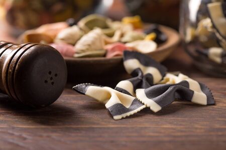 various colourful uncooked pasta over wooden background