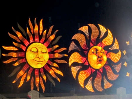 two orange and red illuminated sun figures on a seaside displayの写真素材