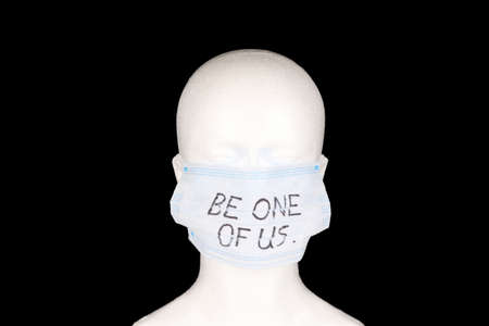 be one of us written on a face mask placed on a mannequin with black background.の写真素材