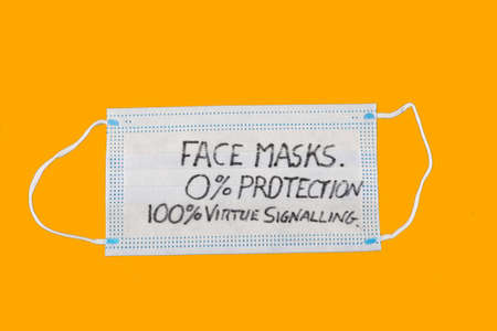 face mask stating zero percent protection and one hundred percent virtue signalling with orange baackground.の写真素材