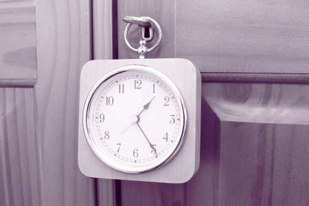 wooden clock hanging on the key of a wooden door with purple coloured filter