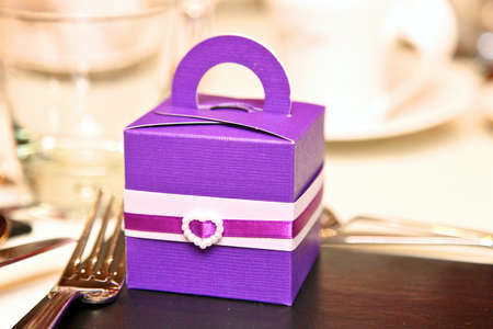 purple coloured favour box with a loveheart at a wedding with fork and glasses in view.