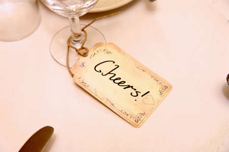 cheers card attached by string to a glass at a wedding.