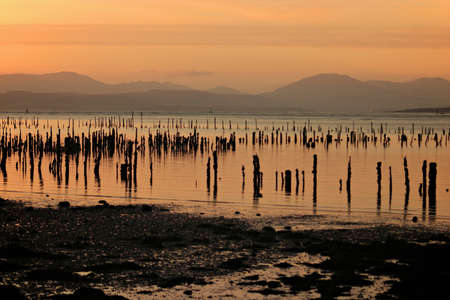 sun setting over the river in greenock with orange sky and hills in view.