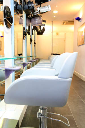 row of white coloured chairs with white walls and mirrors in a hairdressing salonの写真素材