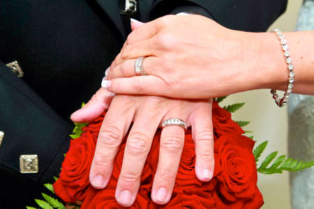 wedding rings against a bouquet of red roses with brides bracelet in view.の写真素材