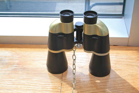 a pair of black and gold binoculars sat on the windowsill next to the window.の写真素材