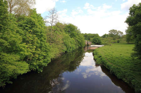 river ambling through the park in summer time with clouds and trees reflecting off the river.の写真素材