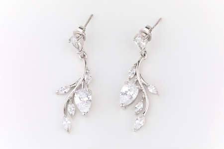 heart shaped silver earrings placed against a white backgroundの写真素材