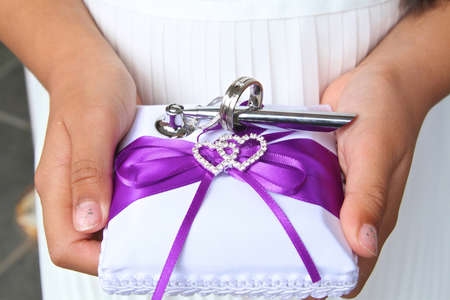 flower girl holding wedding ring on a cushion with purple ribbon.の写真素材