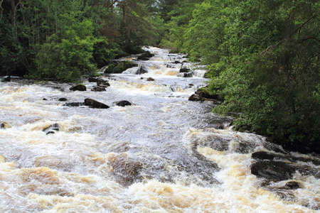 wide angle view of water cascading over the rocks with trees on either side of the embankment.の写真素材