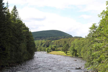 flowing river Tay in Scotland with trees on either side and hill in the backgroundの写真素材