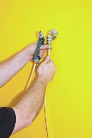 picture of a man demonstrating how to operate a jet spray nozzle against a yellow background.の写真素材