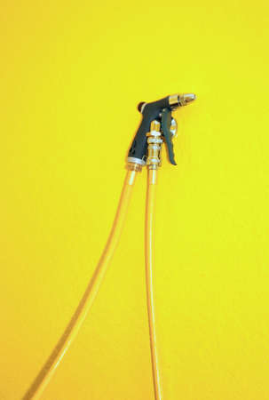 black coloured jet spray with hose placed against a yellow backgroundの写真素材