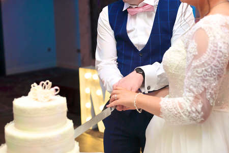 bride and groom cutting the wedding cake with a silver cake knife.の写真素材
