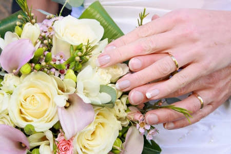 bride and groom ring shots against bouquet of yellow, white, purple and pink flowers for a wedding.の写真素材