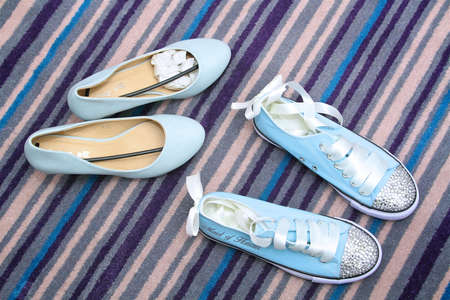 blue coloured bridesmaid and maid of honours shoes for the wedding with stripy carpet in the background.の写真素材