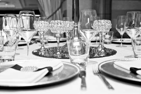 black and white picture of glasses, cutlery, candle holders and display on a table in a restaurant.の写真素材