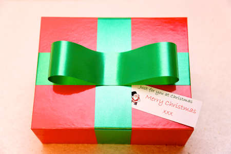 red and green coloured gift box with bow against a plain background.の写真素材