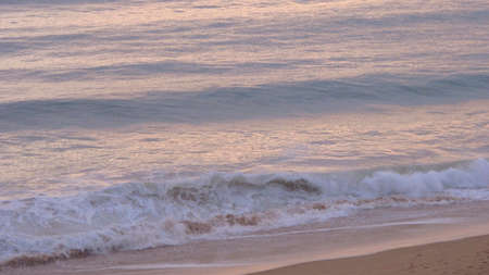 rolling tide coming in on the beach with the sun going down in the Algarve in Portugal.の写真素材