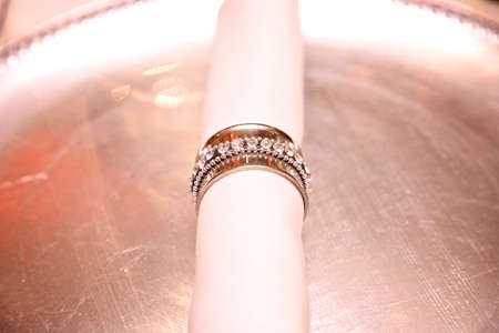 close up of napkin with silver ring holder placed on a silver plate.
